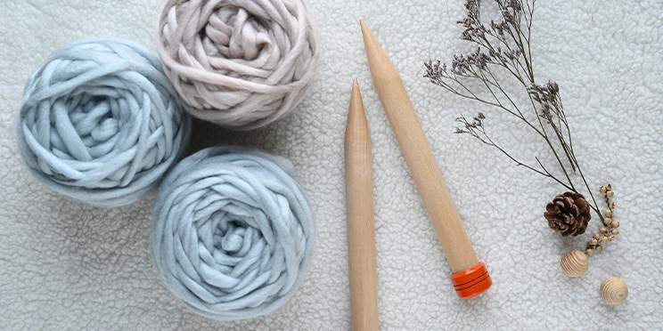 Wolle und Stricknadeln auf einem weißen Tuch